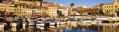 a group of boats docked in a harbor with buildings at Vieux port de Cannes in Cannes