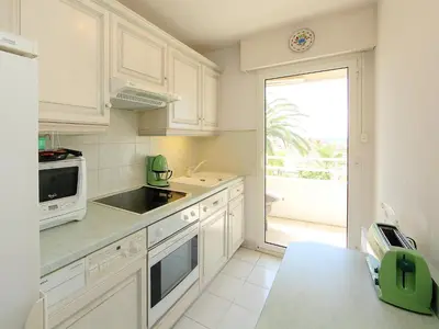 a kitchen with white cabinets and a large window at Apartment Riviera Park-1 by Interhome in Cannes