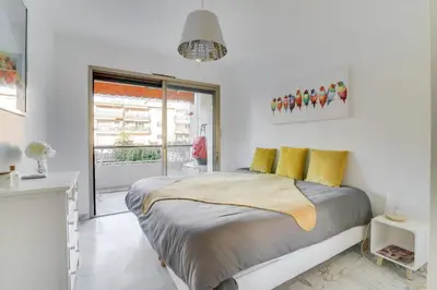 a white bedroom with a large bed with yellow pillows at Superb 1 bedroom appartement - close to Croisette in Cannes