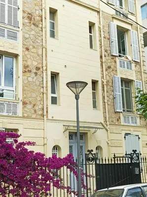 a street light in front of a building with purple flowers at Le Salvator in Cannes