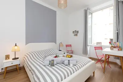 a white bedroom with a bed with a dog laying on it at 2 rooms apartment, near the sea and local market in Cannes