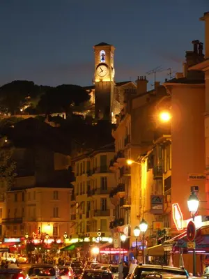 a clock tower on top of a city at night at 2 rooms apartment, near the sea and local market in Cannes