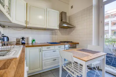 a kitchen with white cabinets and a table with chairs at IMMOGROOM - EXCLUSIVE - Terrace - Amazing quiet place - Wifi in Cannes