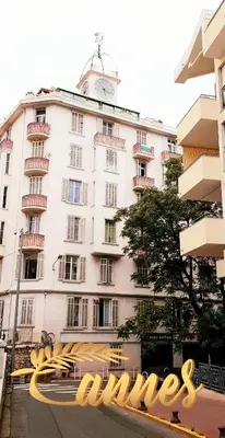a white building with a clock tower on top of it at Studio Cosy centre Cannes in Cannes