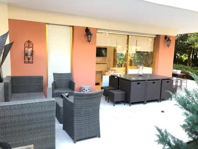 an outdoor patio with wicker chairs and a table at Luxe apartment center 6pers 300m2 privare garden in Cannes