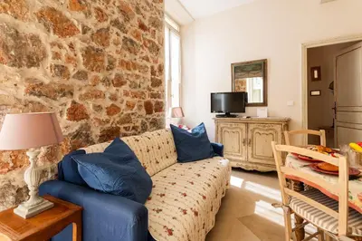 a living room with a couch and a stone wall at Frères Pradignac in Cannes