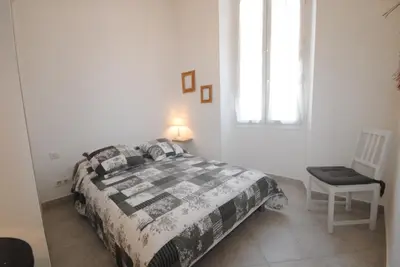 a bedroom with a bed and a chair and a window at Frères Pradignac in Cannes