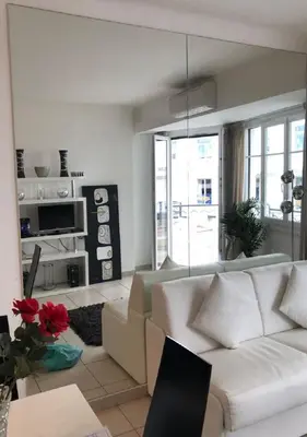 a living room with a white couch and a large window at Ô Palais des Iles Two Bedroom Cannes in Cannes