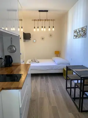 a bedroom with a bed and a kitchen with a table at Studio Vagliano in Cannes