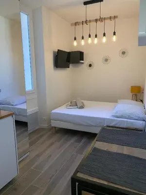 a bedroom with two beds and a tv on the wall at Studio Vagliano in Cannes
