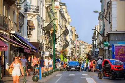 a crowd of people walking down a busy city street at Studio Vagliano in Cannes