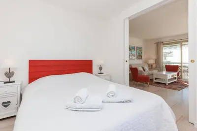 a white bedroom with a white bed and a living room at High-Standard 2-Bedroom Apartment with Sea View and Large Terrace in Cannes