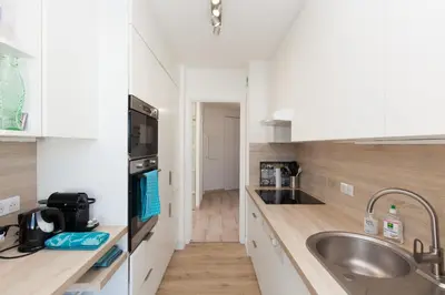 a kitchen with white cabinets and a sink and a counter at High-Standard 2-Bedroom Apartment with Sea View and Large Terrace in Cannes