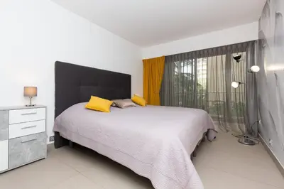 a bedroom with a bed with yellow pillows and a window at 2-Br apartment 2 minutes from the beach parking in Cannes