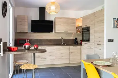 a kitchen with wooden cabinets and a table and chairs at 2-Br with Garden and Pool in the Heart of Palm Beach in Cannes
