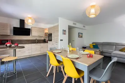 a kitchen and living room with a table and yellow chairs at 2-Br with Garden and Pool in the Heart of Palm Beach in Cannes