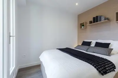 a bedroom with a white bed with black and white pillows at Haven of Peace 1-Br Terrace with Sea View & Pool in Cannes
