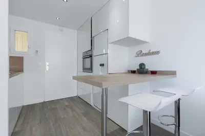 a kitchen with white cabinets and a table and a white chair at Haven of Peace 1-Br Terrace with Sea View & Pool in Cannes