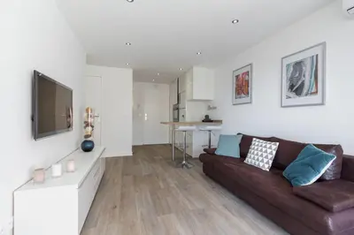a living room with a brown couch and a tv at Haven of Peace 1-Br Terrace with Sea View & Pool in Cannes