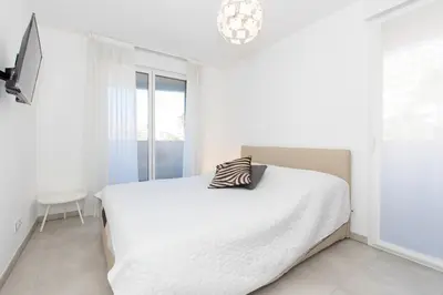 a white bedroom with a bed with a pillow on it at Renovated 2-Br Apartment with Terrace and Pool in Cannes