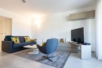 a living room with a couch and a chair and a tv at Renovated 2-Br Apartment with Terrace and Pool in Cannes