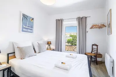 a bedroom with a large white bed and a window at Joli appartement à côté du Palais des Festivals in Cannes