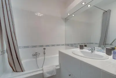 a white bathroom with a sink and a shower at Appartement Palais Milton in Cannes