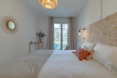 a bedroom with a large white bed with a mirror at Appartement Palais Milton in Cannes