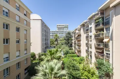 an apartment building with palm trees and buildings at Appartement Palais Milton in Cannes