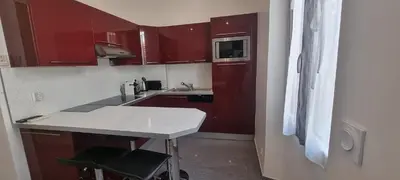 a small kitchen with red cabinets and a counter at One Bedroom André in Cannes