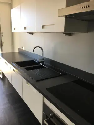 a kitchen with a sink and a black counter top at Appartement Le Palais Des Iles in Cannes