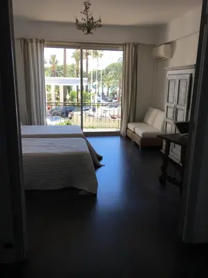 a bedroom with a bed and a couch and a window at Appartement Le Palais Des Iles in Cannes