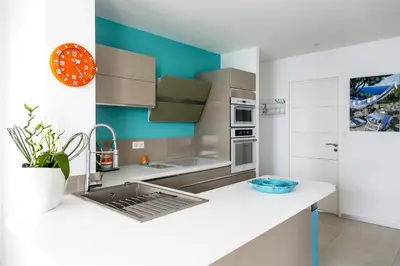 a kitchen with a white counter and a blue wall at PLAGE Ground floor apartment on seafront with large terrace in Cannes