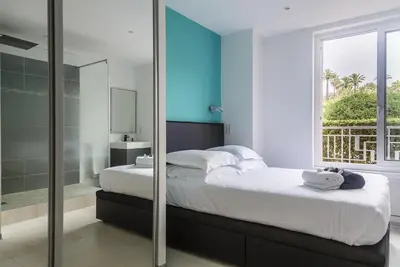 a bedroom with a bed and a glass shower at PLAGE Ground floor apartment on seafront with large terrace in Cannes