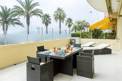 a table and chairs on a balcony with palm trees at PLAGE Ground floor apartment on seafront with large terrace in Cannes