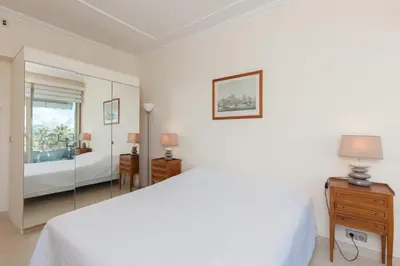 a white bedroom with a bed and a mirror at Sea View Cannes Croisette in Front of the Sea in Cannes