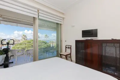 a bedroom with a bed and a television and a balcony at Sea View Cannes Croisette in Front of the Sea in Cannes