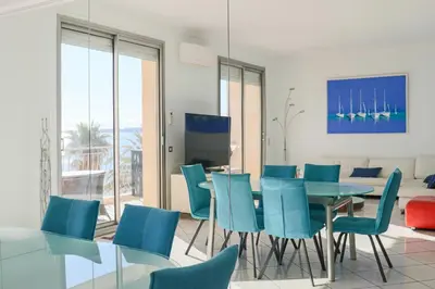 a dining room with a table and blue chairs at Superb Bright Apartment with Sea View in Cannes