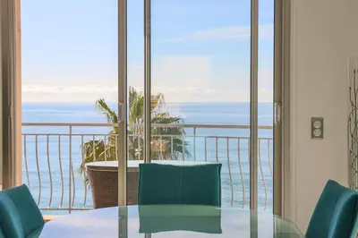 a table and chairs in a room with a view of the ocean at Superb Bright Apartment with Sea View in Cannes