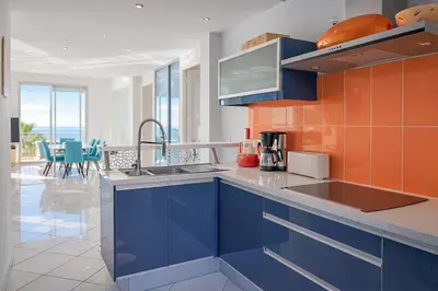 a kitchen with blue cabinets and orange tiles at Superb Bright Apartment with Sea View in Cannes