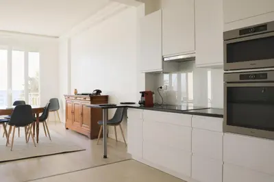 a kitchen with white cabinets and a table and chairs at IMMOGROOM - SEA VIEW - 2 min from beach - CONGRESSBEACHES in Cannes