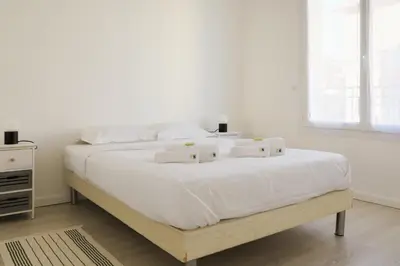 a white bedroom with a large bed with white sheets at IMMOGROOM - SEA VIEW - 2 min from beach - CONGRESSBEACHES in Cannes