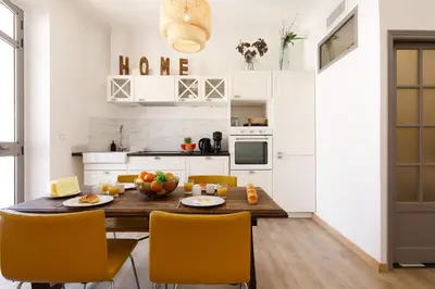 a kitchen and dining room with a wooden table and chairs at La Colline YourHostHelper in Cannes