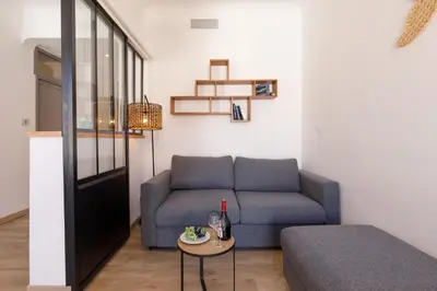a living room with a blue couch and a table at La Colline YourHostHelper in Cannes