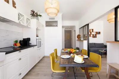 a kitchen and dining room with a table and yellow chairs at La Colline YourHostHelper in Cannes
