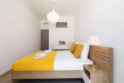 a bedroom with a large bed with a yellow blanket at La Colline YourHostHelper in Cannes