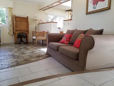 a living room with a brown couch with red pillows at Haus mit Garten über der Bucht von Cannes in Vallauris