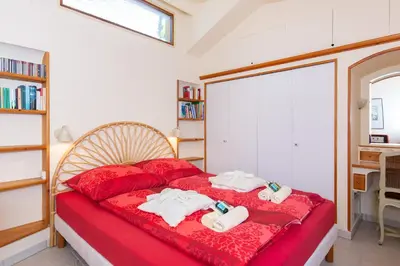 a bedroom with a red bed with towels on it at Haus mit Garten über der Bucht von Cannes in Vallauris