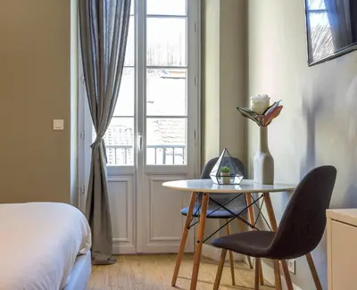 a room with a table and chairs and a bed and a window at Agences des Résidences - Rue Commandant André in Cannes