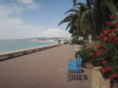 a blue bench sitting on a sidewalk next to the beach at Prime Location Hyper Center Ideal for Couples & Families - Walk Everywhere - SMART by Totolulucannes in Cannes